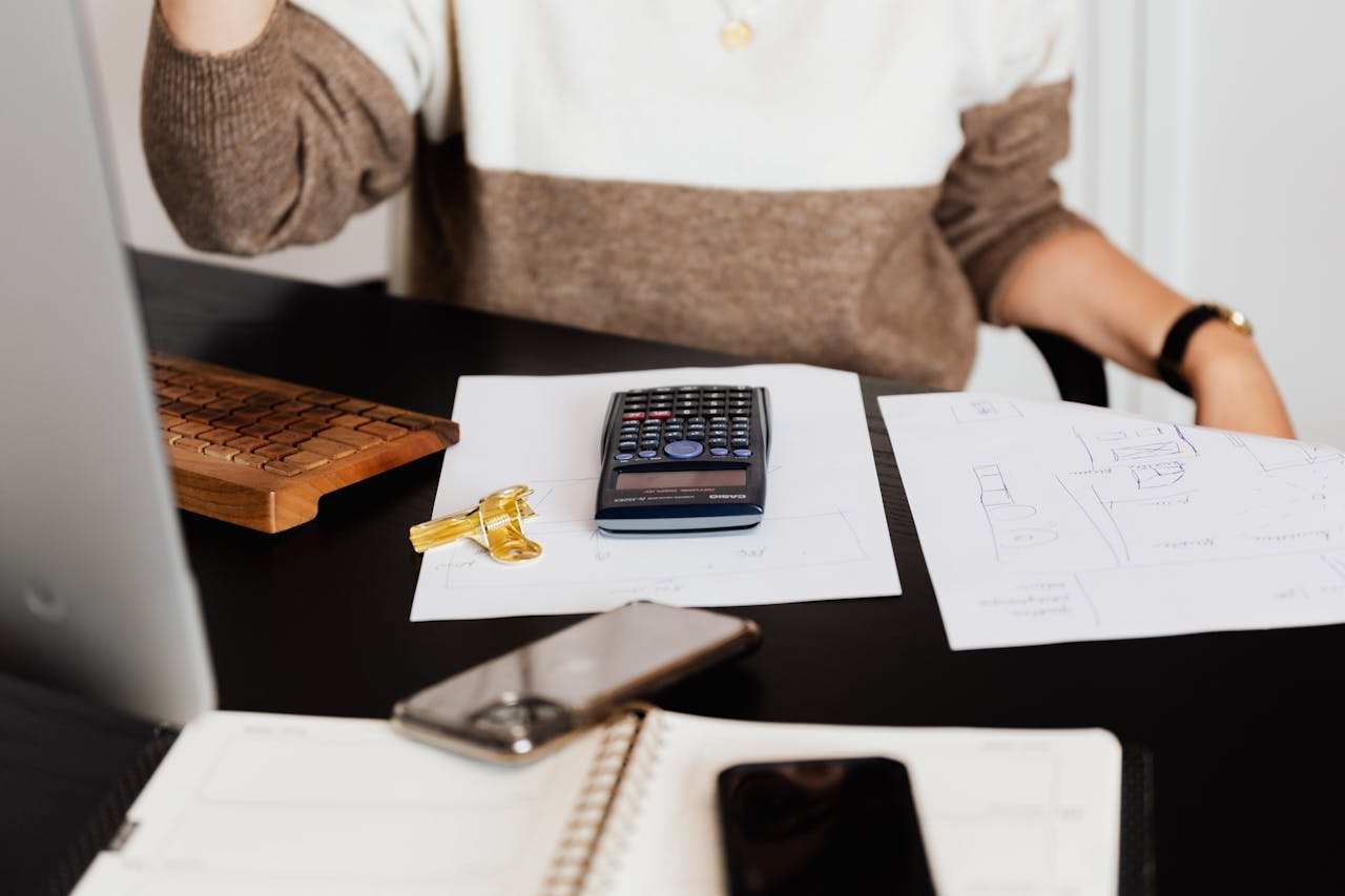 A business desk setup with a calculator, papers, and a keyboard, reflecting a work environment.
